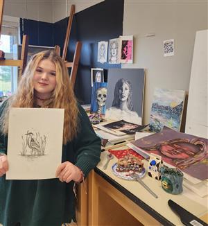  Addison M. holds her award-winning art piece, with the rest of her portfolio behind her.